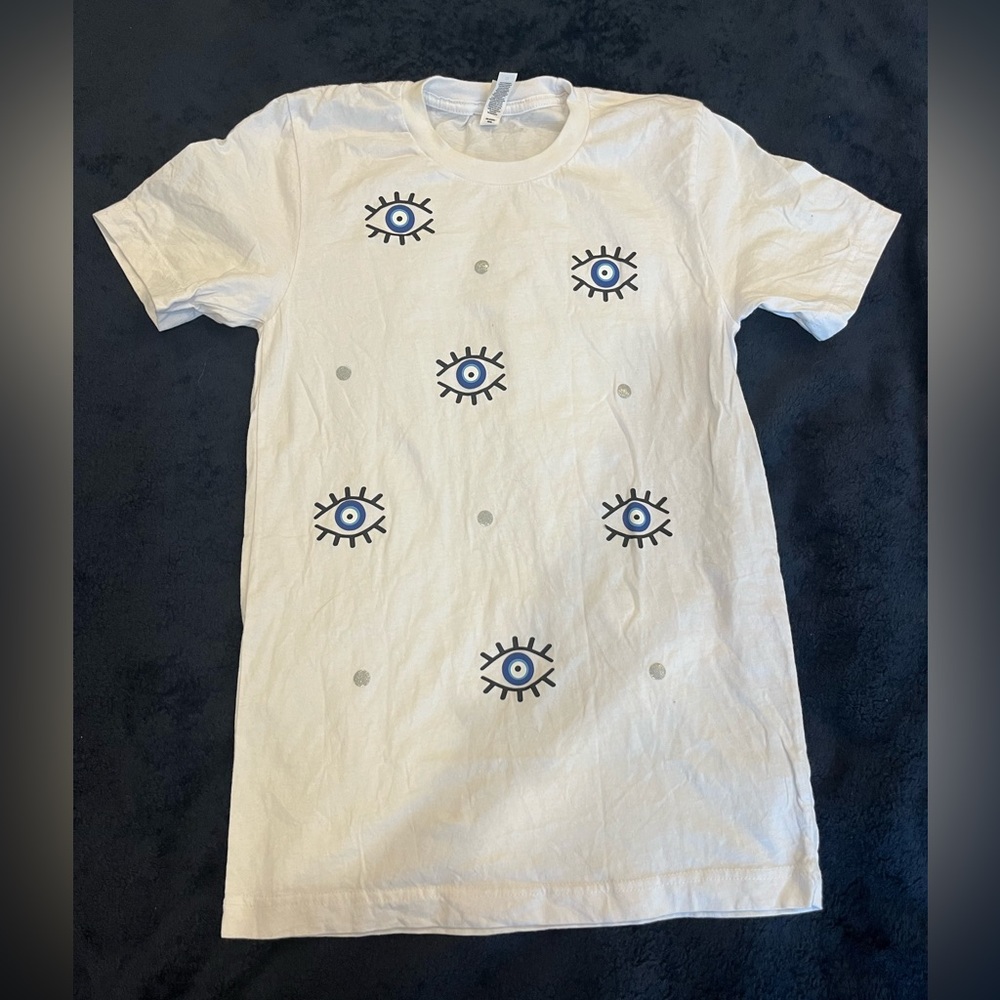 white T-shirt with evil eye and polka dot designs.